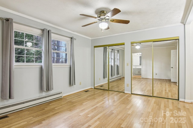 unfurnished bedroom featuring a baseboard radiator, ceiling fan, multiple closets, and light hardwood / wood-style floors