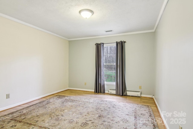 spare room featuring a textured ceiling, ornamental molding, baseboard heating, and light hardwood / wood-style flooring