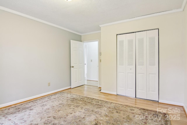 unfurnished bedroom featuring crown molding, a closet, and hardwood / wood-style flooring