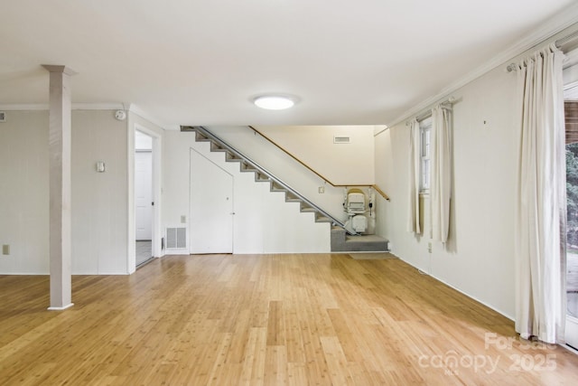 basement featuring light wood-type flooring and crown molding