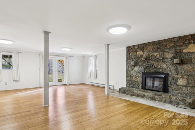 unfurnished living room with crown molding, a stone fireplace, light hardwood / wood-style flooring, and a baseboard heating unit