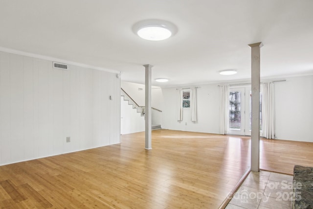 basement with wooden walls, light hardwood / wood-style floors, and crown molding