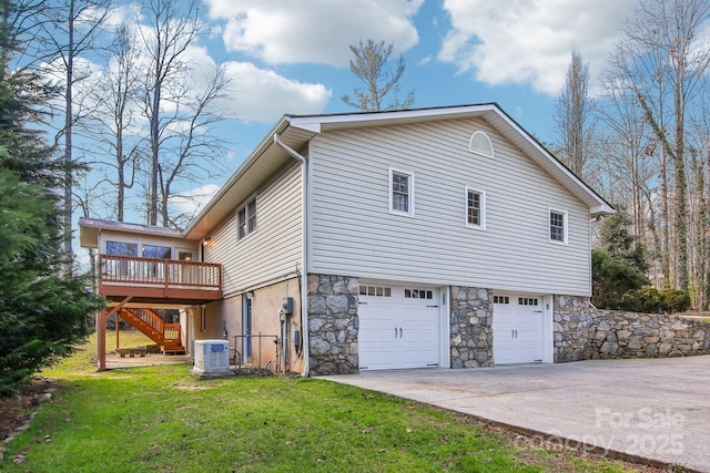 view of side of property featuring a lawn, a garage, a wooden deck, and central AC