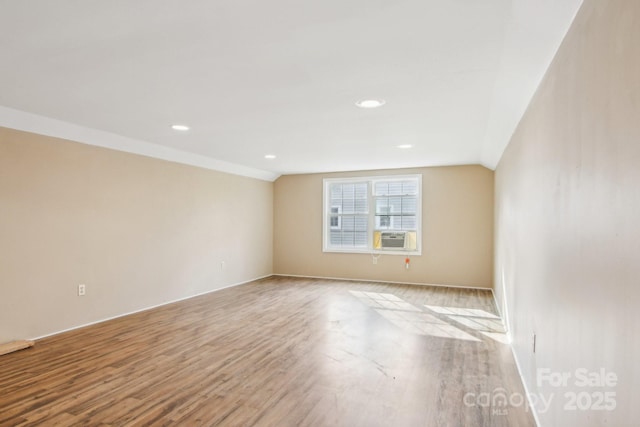 unfurnished room with cooling unit, light wood-type flooring, and vaulted ceiling