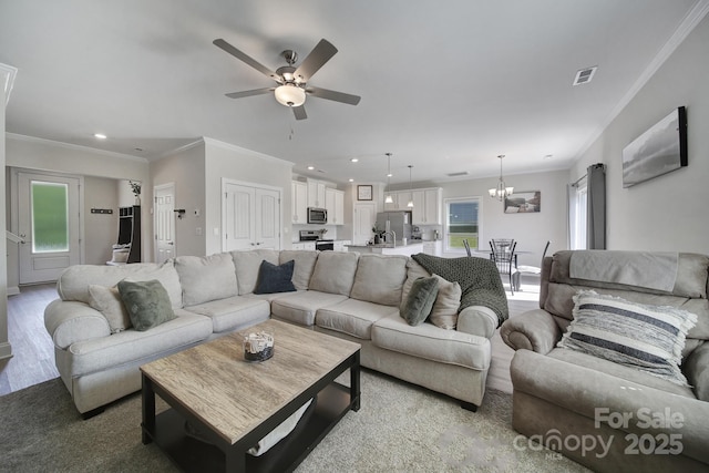 living room with ceiling fan with notable chandelier and ornamental molding