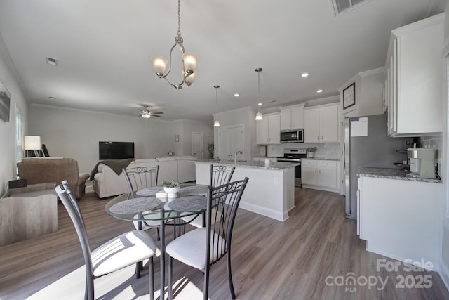 dining area featuring ceiling fan with notable chandelier, sink, crown molding, and light hardwood / wood-style flooring