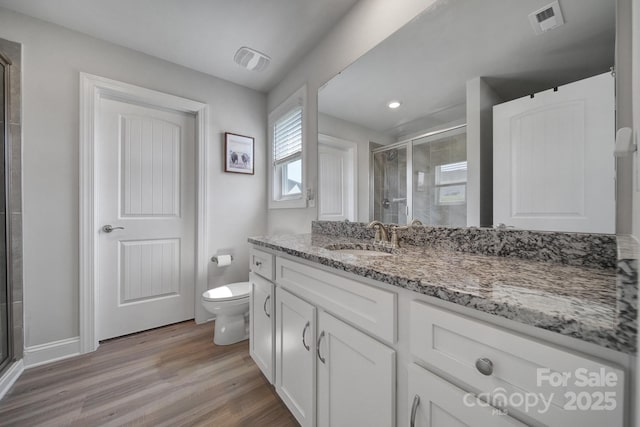 bathroom featuring hardwood / wood-style floors, vanity, toilet, and a shower with door