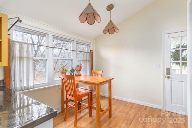 dining room featuring light hardwood / wood-style floors, vaulted ceiling, and plenty of natural light