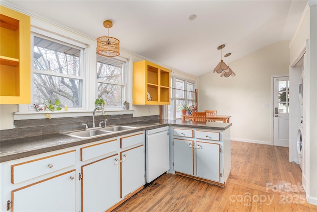 kitchen with lofted ceiling, white dishwasher, hanging light fixtures, kitchen peninsula, and white cabinetry