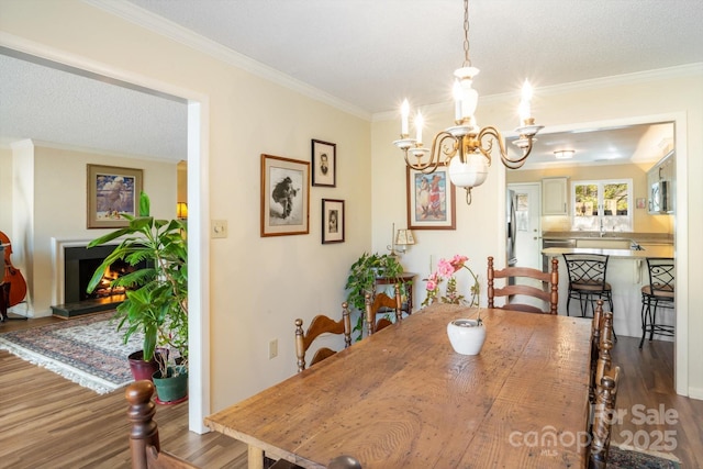 dining area featuring an inviting chandelier, crown molding, wood-type flooring, and a textured ceiling