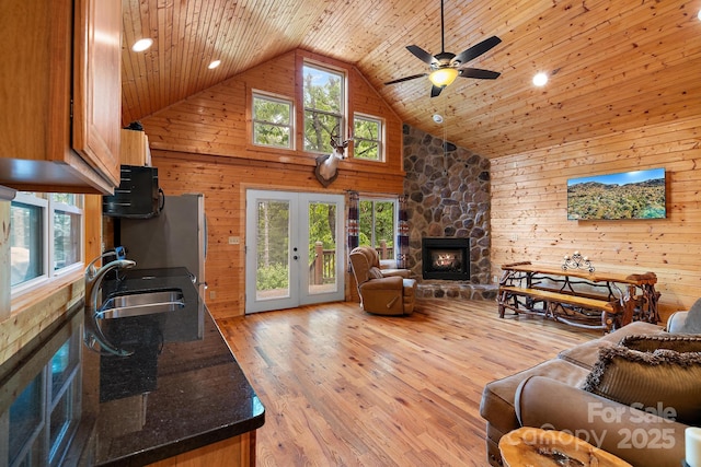 living room featuring wood walls, wooden ceiling, sink, and french doors