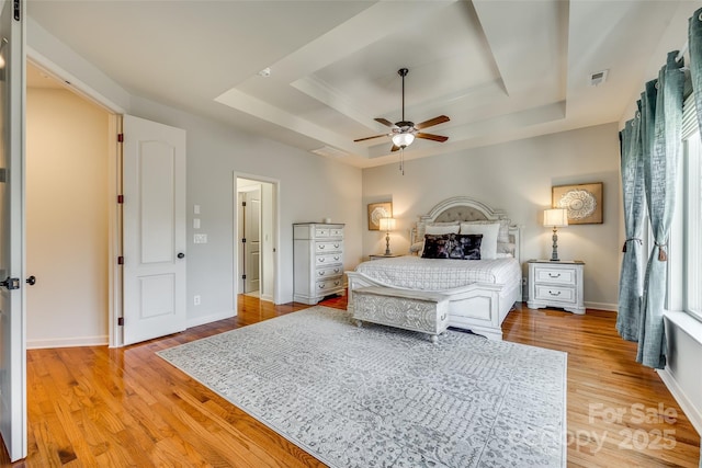 bedroom with a tray ceiling, ceiling fan, and hardwood / wood-style flooring