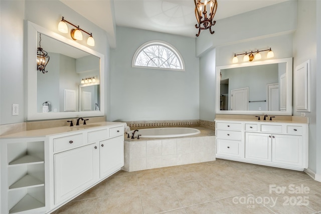 bathroom with vanity, tile patterned flooring, a relaxing tiled tub, and an inviting chandelier