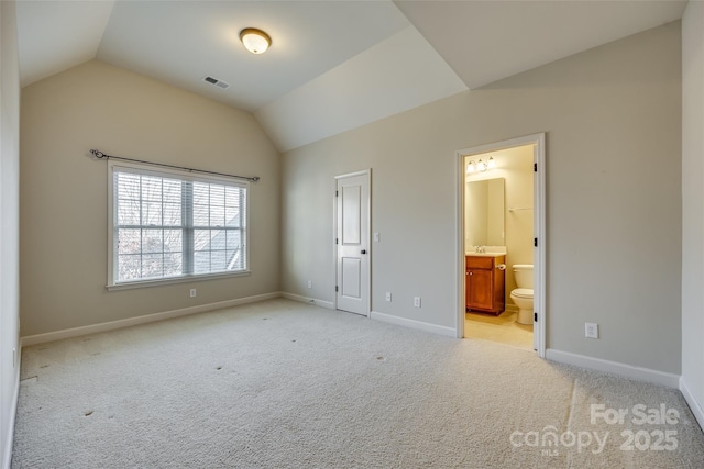 unfurnished bedroom featuring ensuite bathroom, lofted ceiling, and light carpet