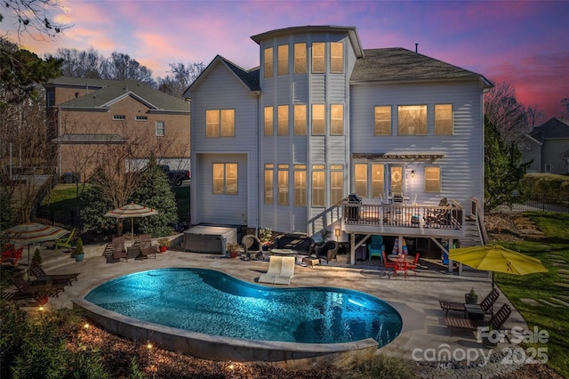 back house at dusk with a swimming pool side deck and a patio area