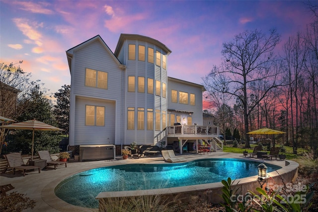 back house at dusk with a swimming pool with hot tub and a patio