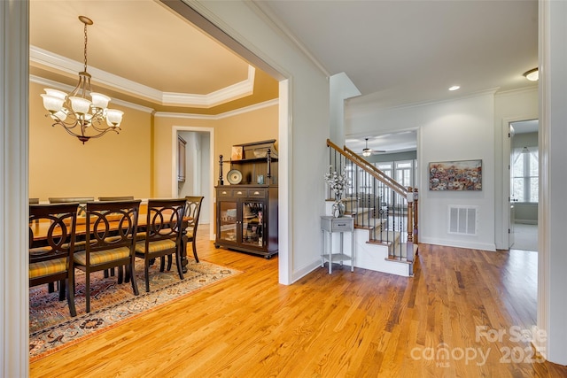 dining area with ceiling fan with notable chandelier, wood-type flooring, and crown molding