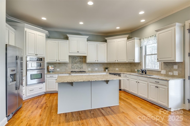 kitchen featuring stainless steel appliances, a kitchen island, sink, light hardwood / wood-style flooring, and white cabinetry