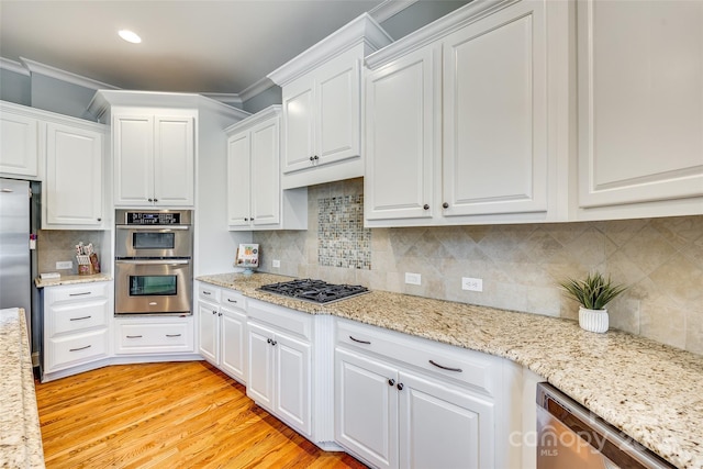 kitchen with backsplash, white cabinetry, stainless steel appliances, and ornamental molding