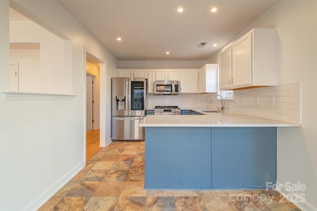 kitchen with stainless steel appliances, sink, white cabinets, and kitchen peninsula