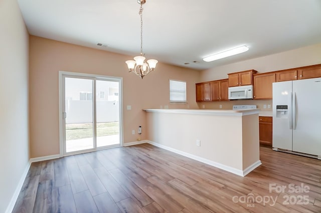 kitchen with a wealth of natural light, a notable chandelier, light hardwood / wood-style floors, pendant lighting, and white appliances