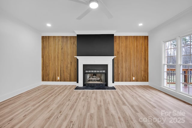 unfurnished living room with ceiling fan, ornamental molding, and light hardwood / wood-style floors