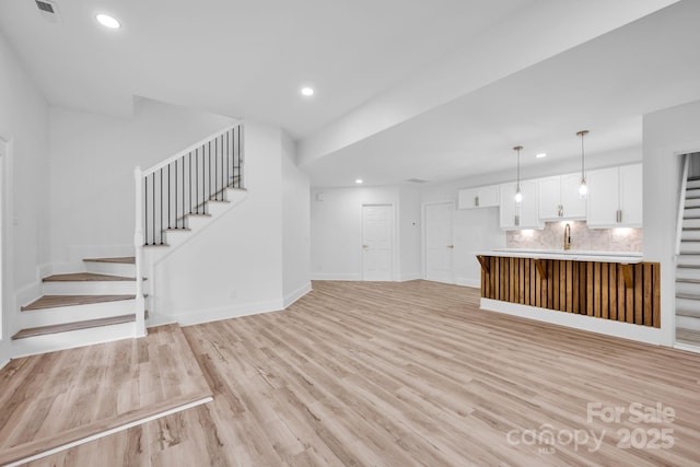 unfurnished living room with sink and light hardwood / wood-style flooring