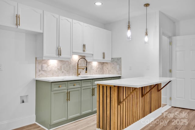 kitchen with hanging light fixtures, backsplash, and light wood-type flooring