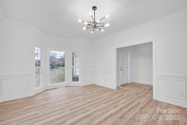 empty room with crown molding, a chandelier, and light wood-type flooring