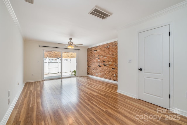 empty room featuring light hardwood / wood-style flooring, ceiling fan, crown molding, and brick wall