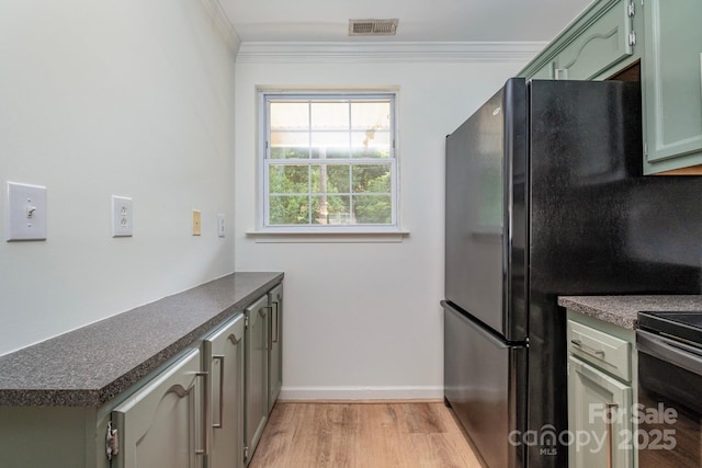 kitchen featuring stainless steel electric range oven, light hardwood / wood-style flooring, green cabinetry, black refrigerator, and ornamental molding