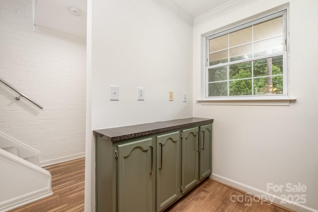 clothes washing area with crown molding and light hardwood / wood-style flooring