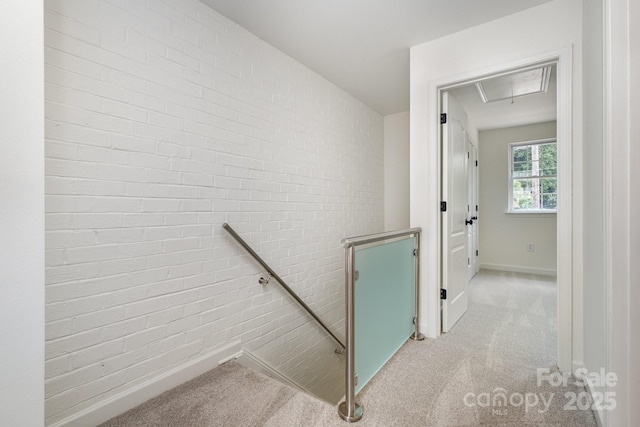 staircase with carpet floors and brick wall