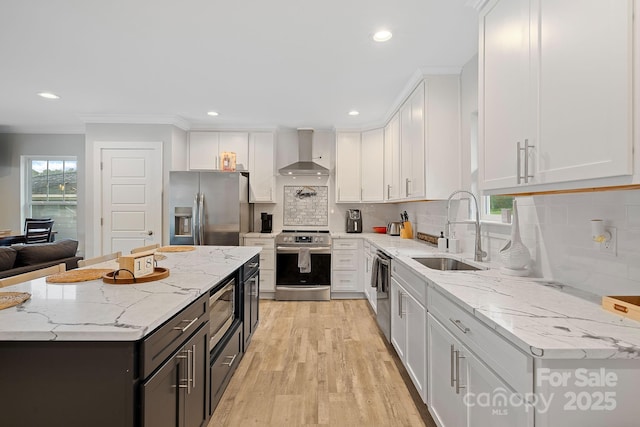 kitchen with sink, white cabinets, stainless steel appliances, and wall chimney range hood