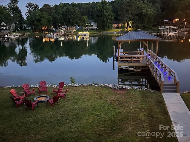 dock area featuring a yard, a water view, and an outdoor fire pit