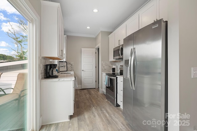 kitchen with white cabinetry, stainless steel appliances, tasteful backsplash, crown molding, and light wood-type flooring