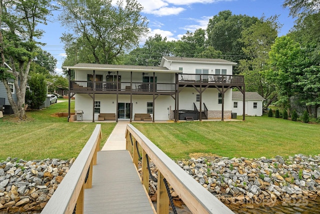 back of house with a yard, a wooden deck, and a hot tub