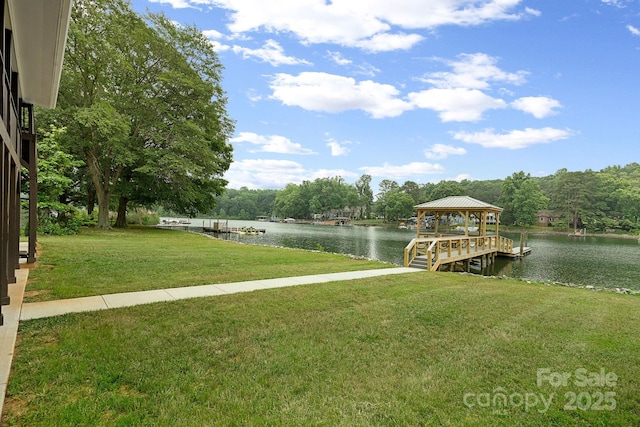 dock area with a gazebo, a water view, and a lawn