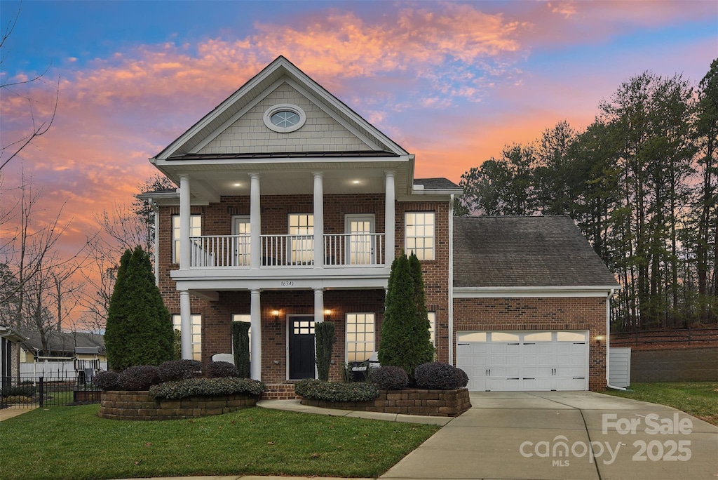 greek revival house with a porch, a balcony, a yard, and a garage