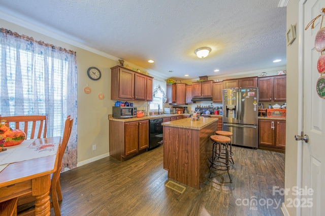 kitchen with a kitchen breakfast bar, a kitchen island, dark wood-type flooring, and appliances with stainless steel finishes