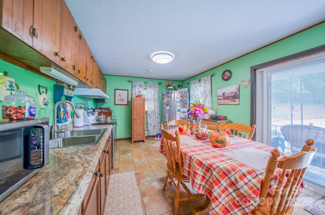 dining area with sink, light tile patterned flooring, and a textured ceiling