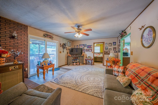 living room with ceiling fan, a textured ceiling, and light wood-type flooring