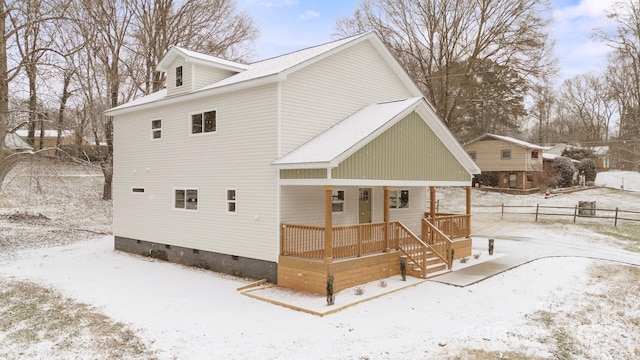 snow covered rear of property with covered porch