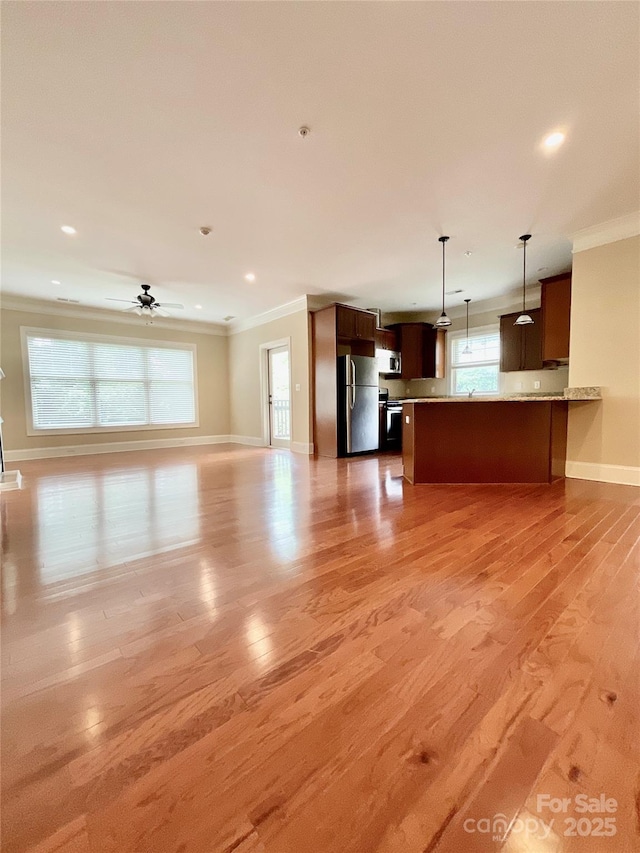 unfurnished living room with ceiling fan, ornamental molding, a healthy amount of sunlight, and light hardwood / wood-style floors