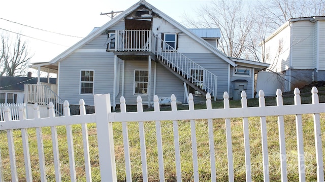 back of house with a lawn and a balcony