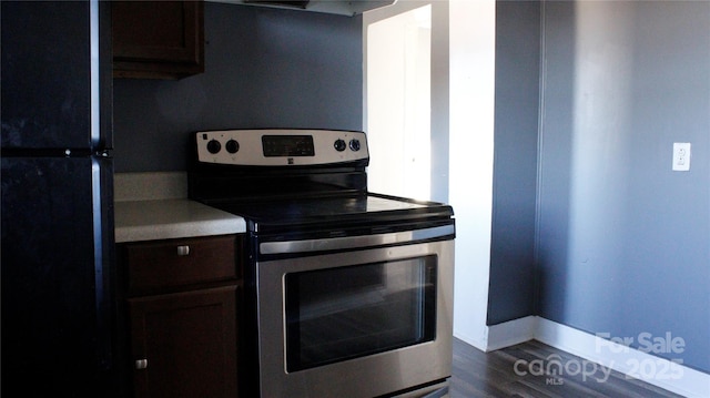 kitchen with black refrigerator, dark hardwood / wood-style flooring, and stainless steel range with electric cooktop