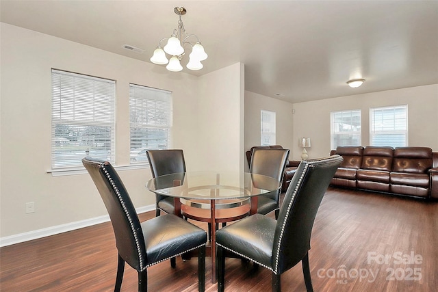 dining area with an inviting chandelier and dark hardwood / wood-style flooring