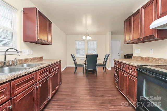 kitchen with pendant lighting, sink, dark hardwood / wood-style flooring, stove, and wall chimney exhaust hood