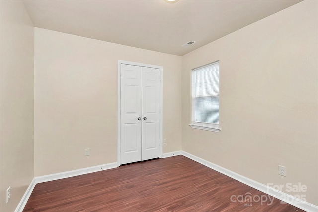 unfurnished bedroom with dark wood-type flooring and a closet