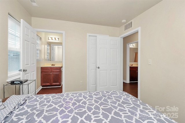 bedroom with ensuite bath, dark hardwood / wood-style flooring, and a closet